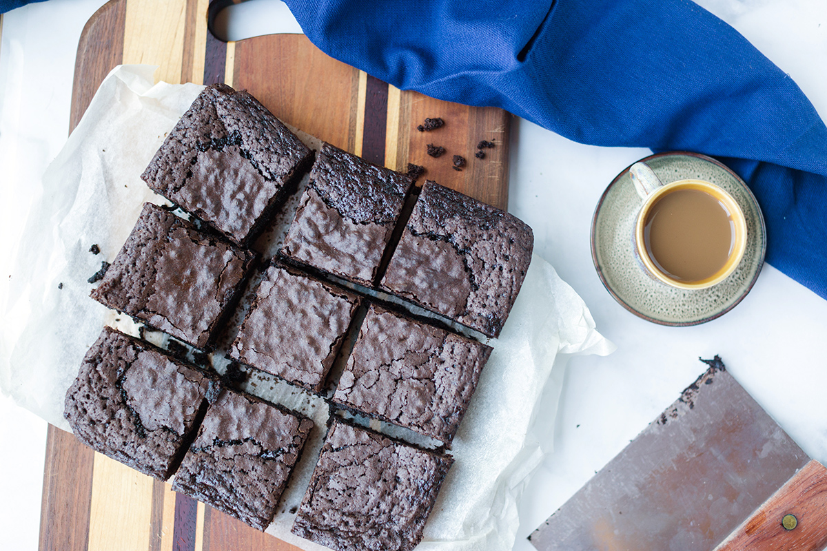 A pan of gluten-free brownies cut into slices with an espresso off to the side