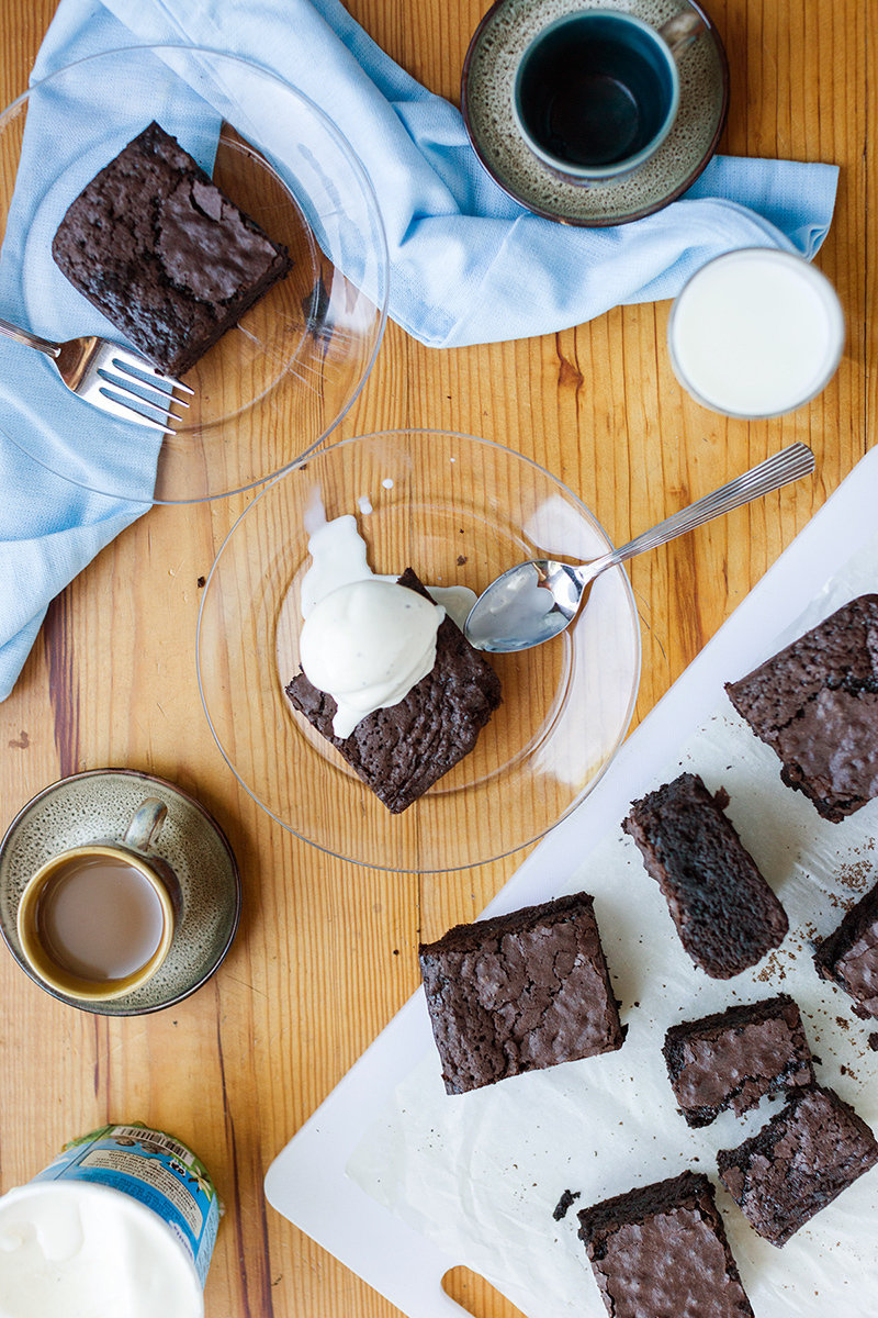 Gluten-free brownies on plates, topped with vanilla bean ice cream
