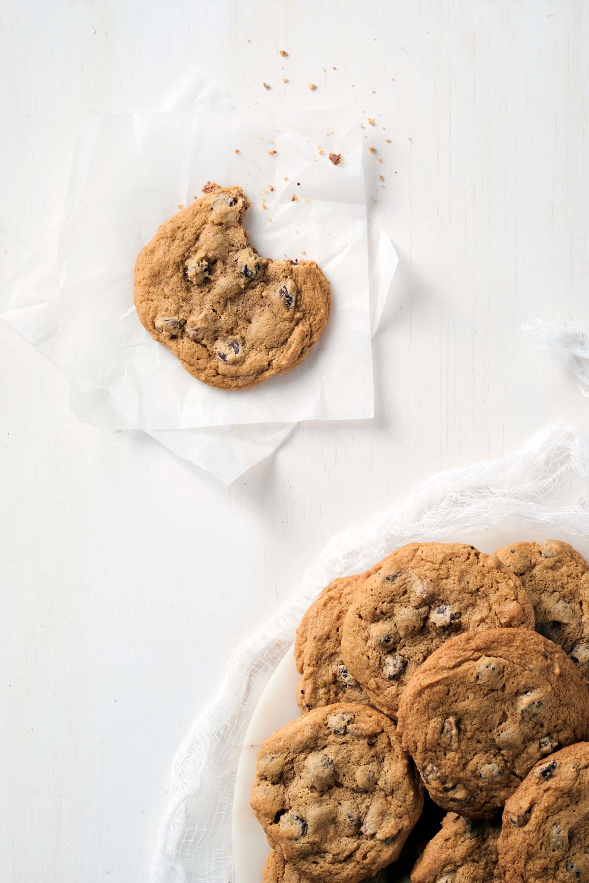 A platter of gluten-free chocolate chip cookies with a single cookie that has a bite taken out of it