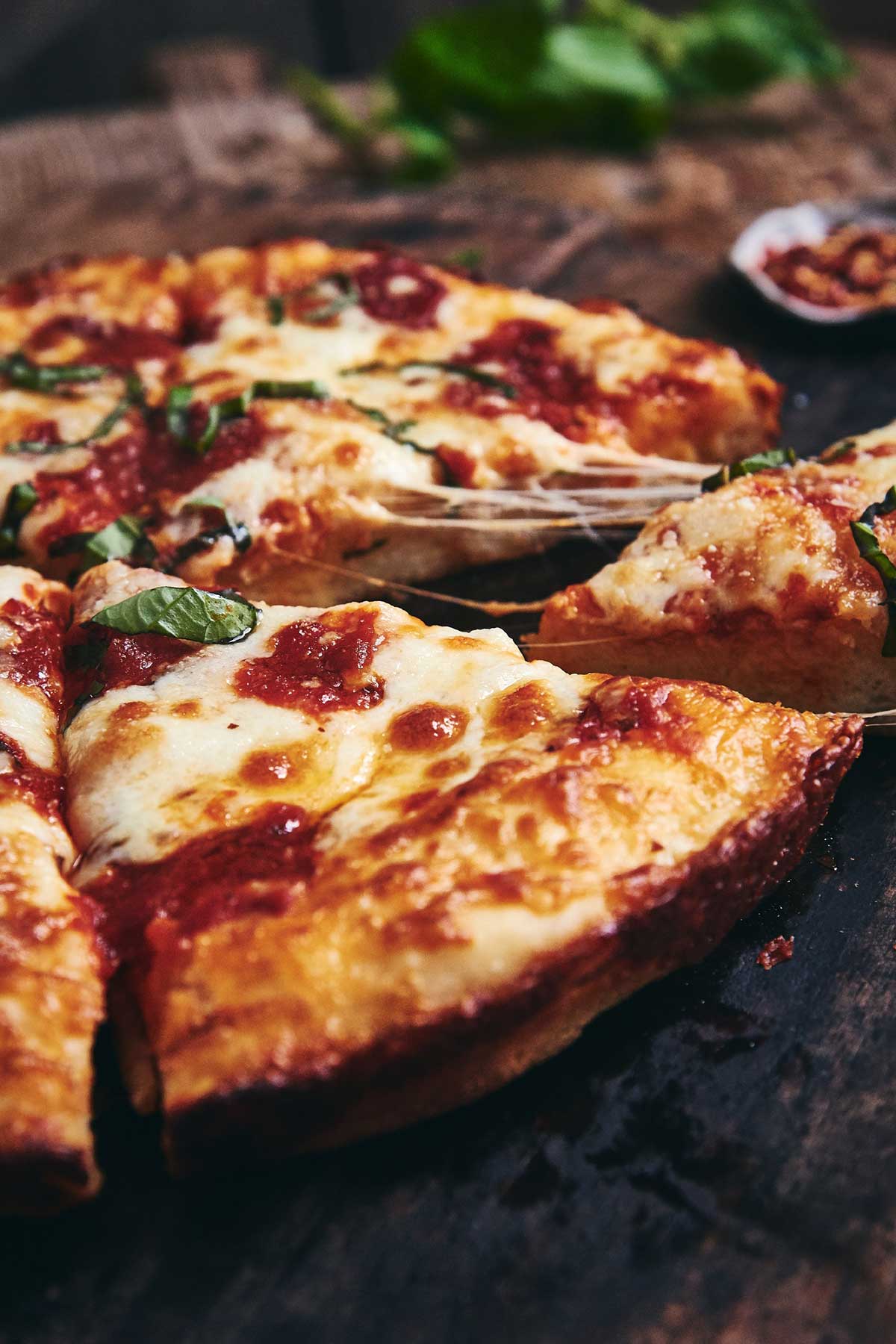 A slice being removed from a freshly baked Gluten-Free Pan Pizza with cheese stretching from the slice