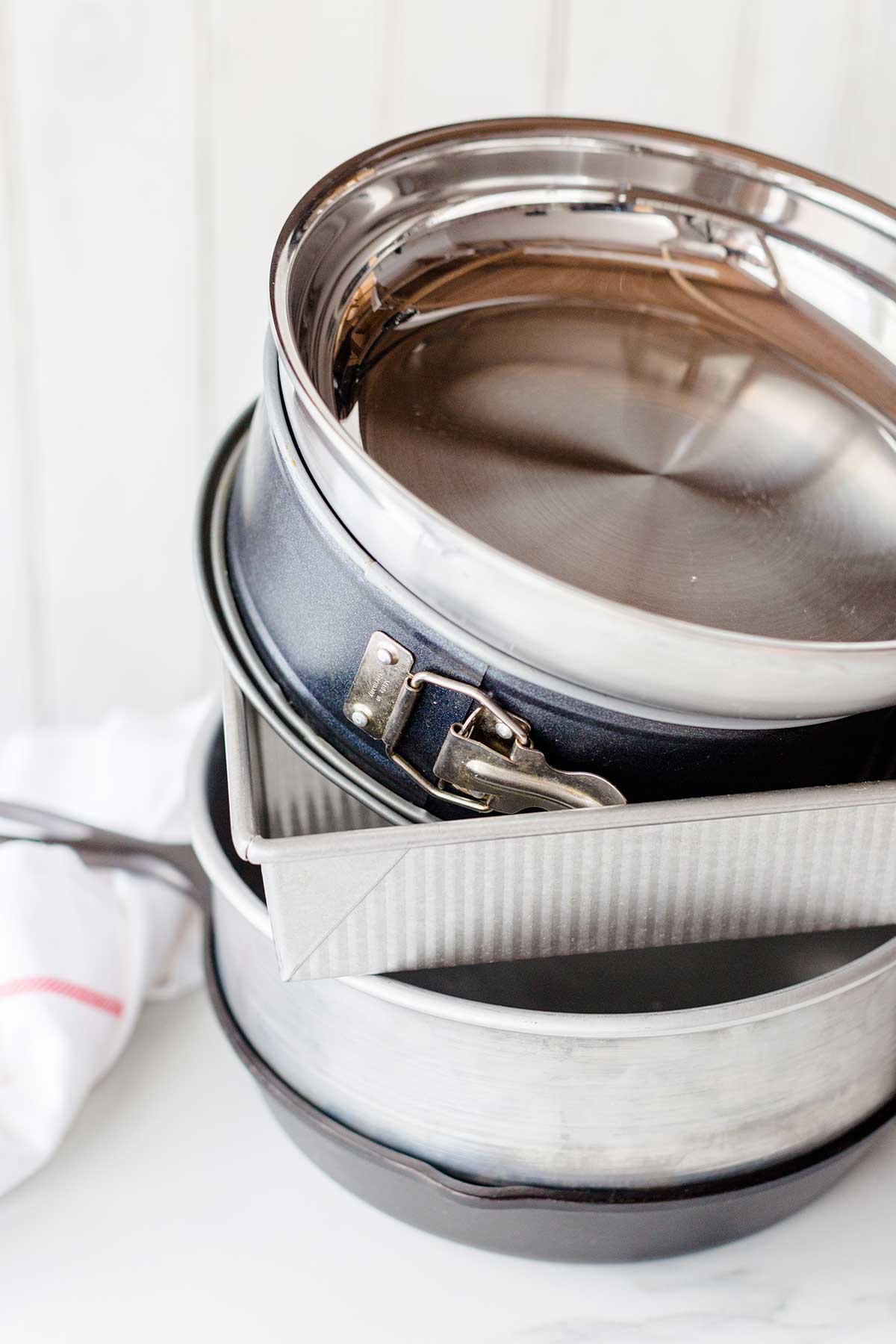 A stack of skillets and pans suitable to bake a gluten-free pan pizza