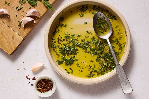 A bowl of garlic-basil oil showing oil infused with basil and garlic.