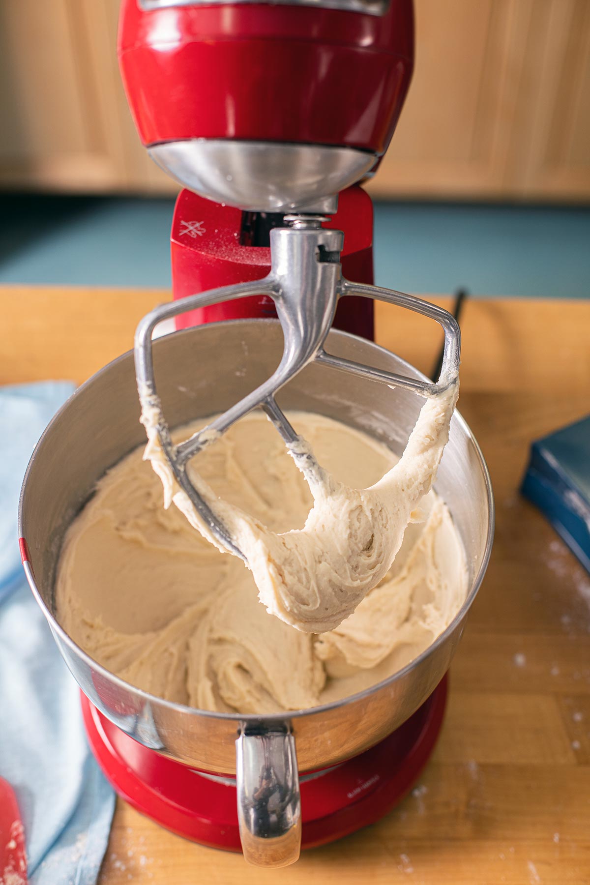 A stand mixer with a paddle attachment and bowl of fully beaten gluten-free cinnamon roll dough