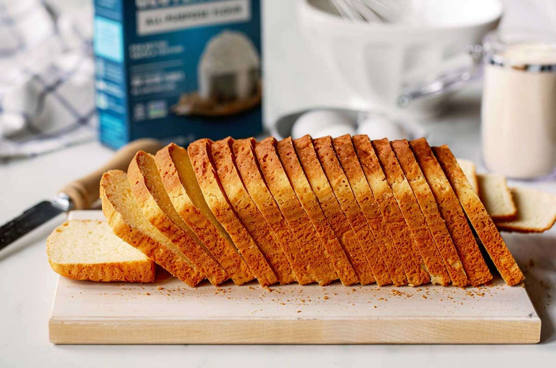 Loaf topped with oats being sliced on cutting board