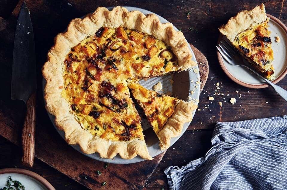 Roasted butternut squash and spinach quiche, one piece cut out on a plate.