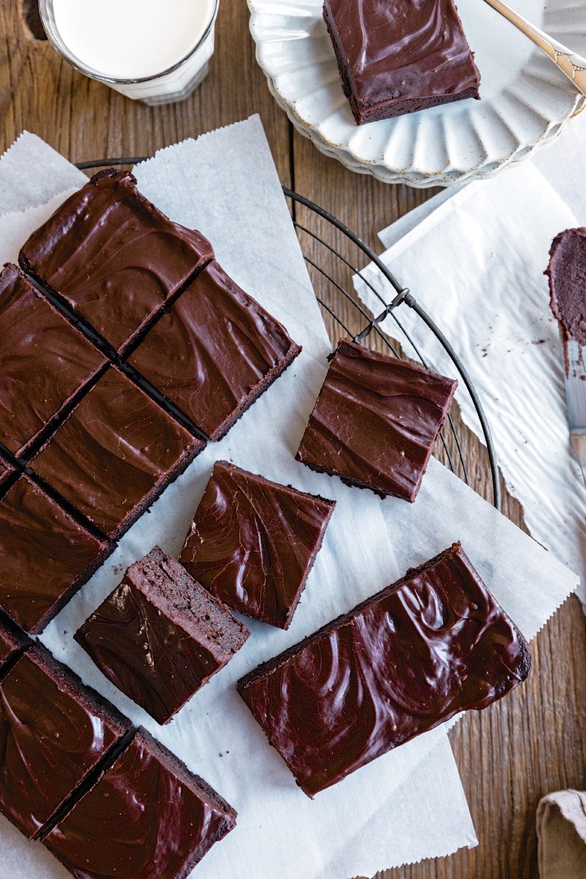 Zucchini chocolate cake cut into squares, some plated, some on a piece of parchment.