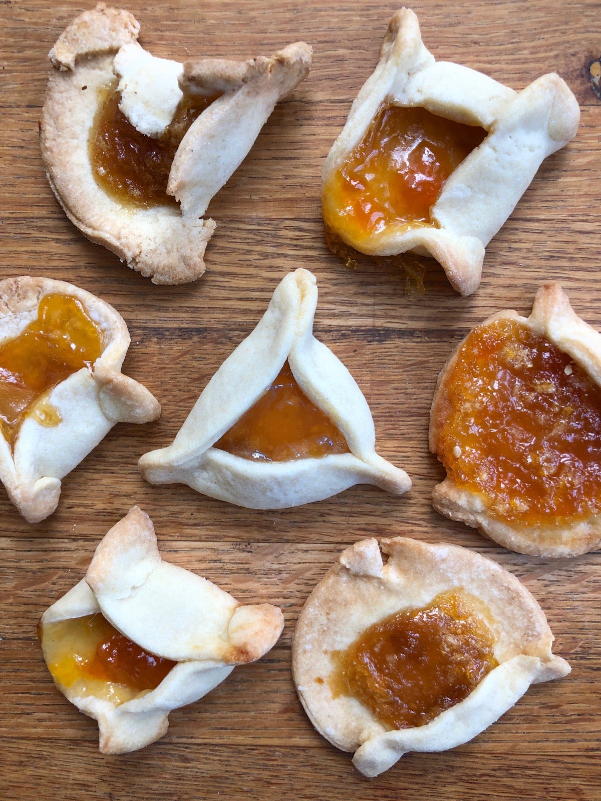 hamantaschen cookies on a table; one perfectly shaped cookie in the center.