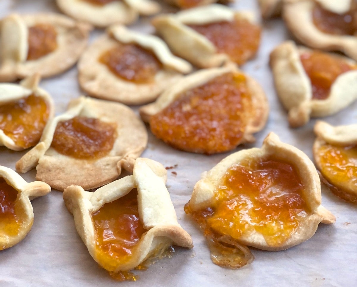 Misshapen hamantaschen cookies on a baking sheet.