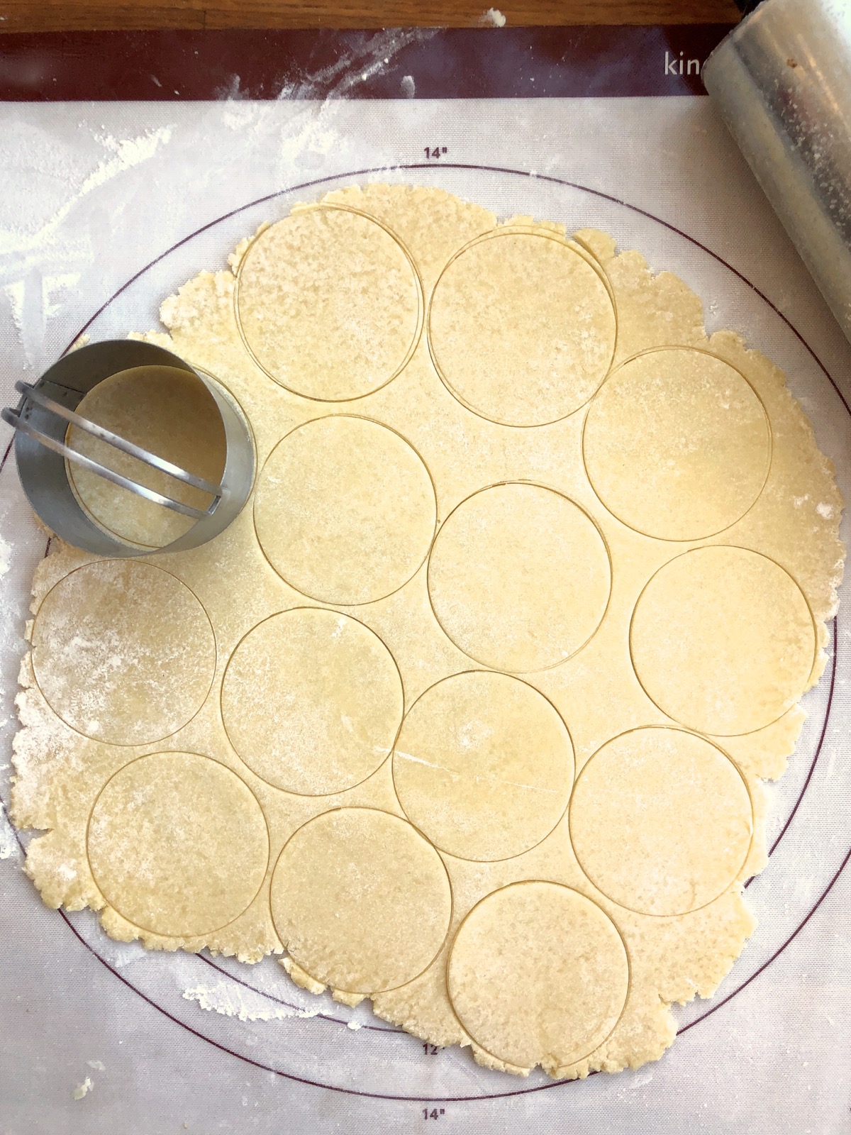 Rolled-out dough with a round biscuit cutter, marked with circles from the biscuit cutter to show where to cut.