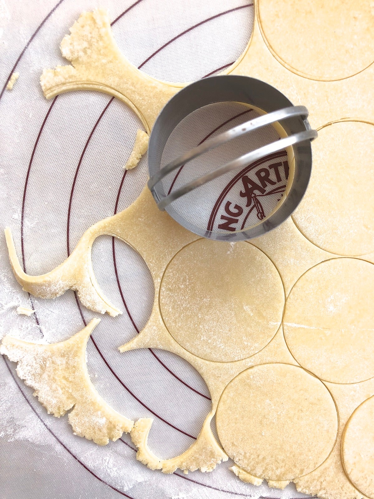 Rolled-out dough being cut with a round biscuit cutter.