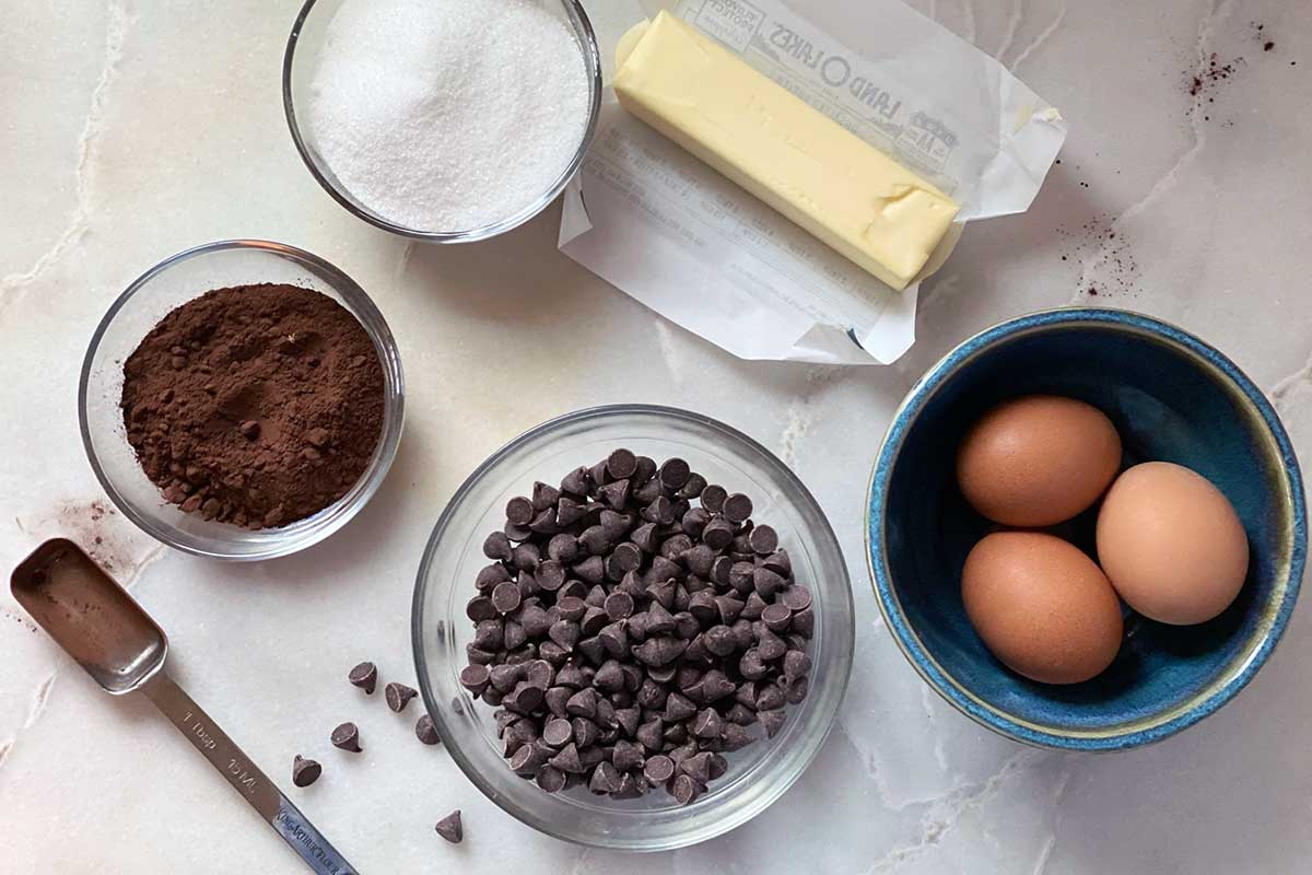 All the ingredients needed to make a flourless chocolate cake, including butter, eggs, chocolate chips