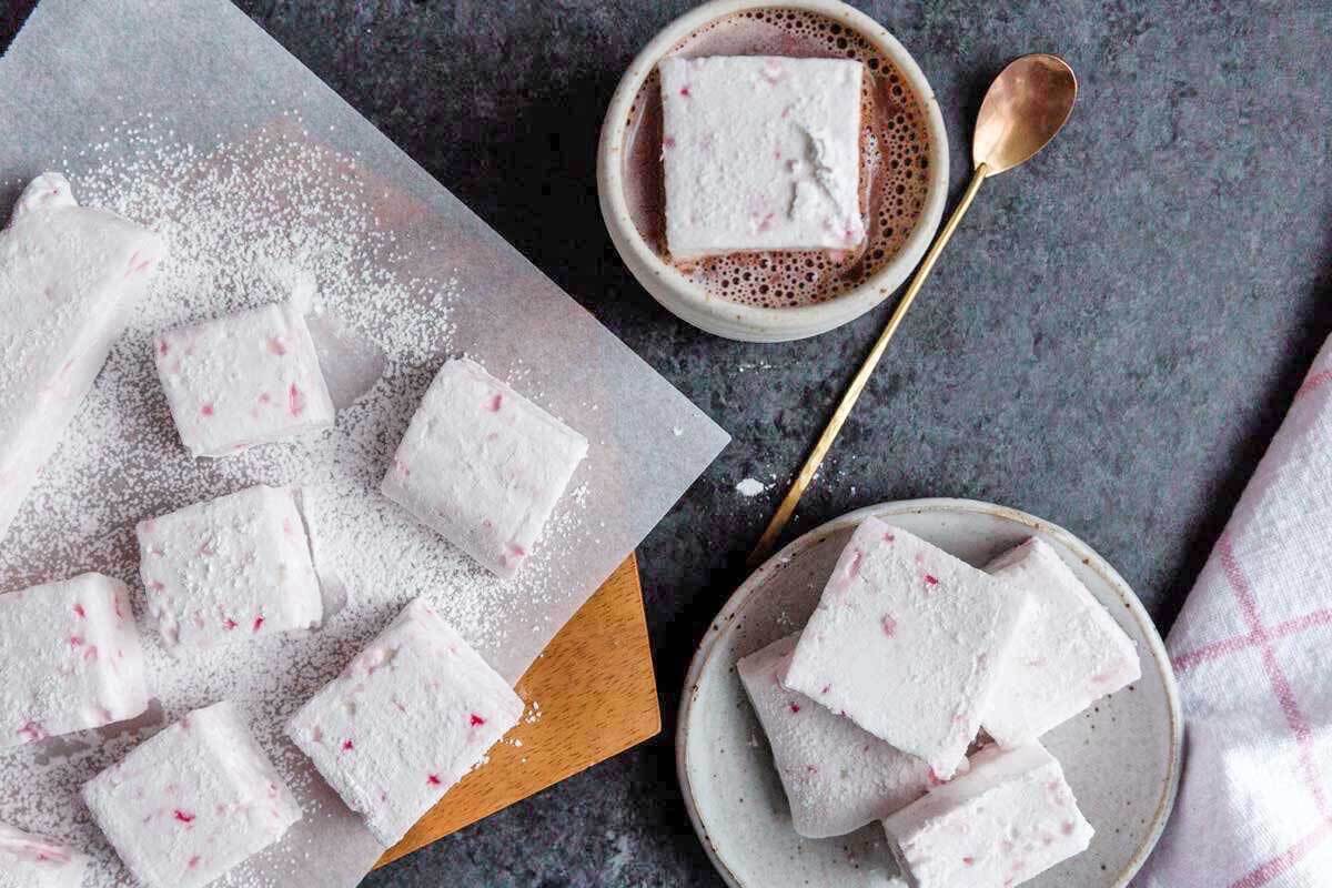 Peppermint marshmallows cut in blocks, some on a plate, some on a  board, one in a cup of hot cocoa.