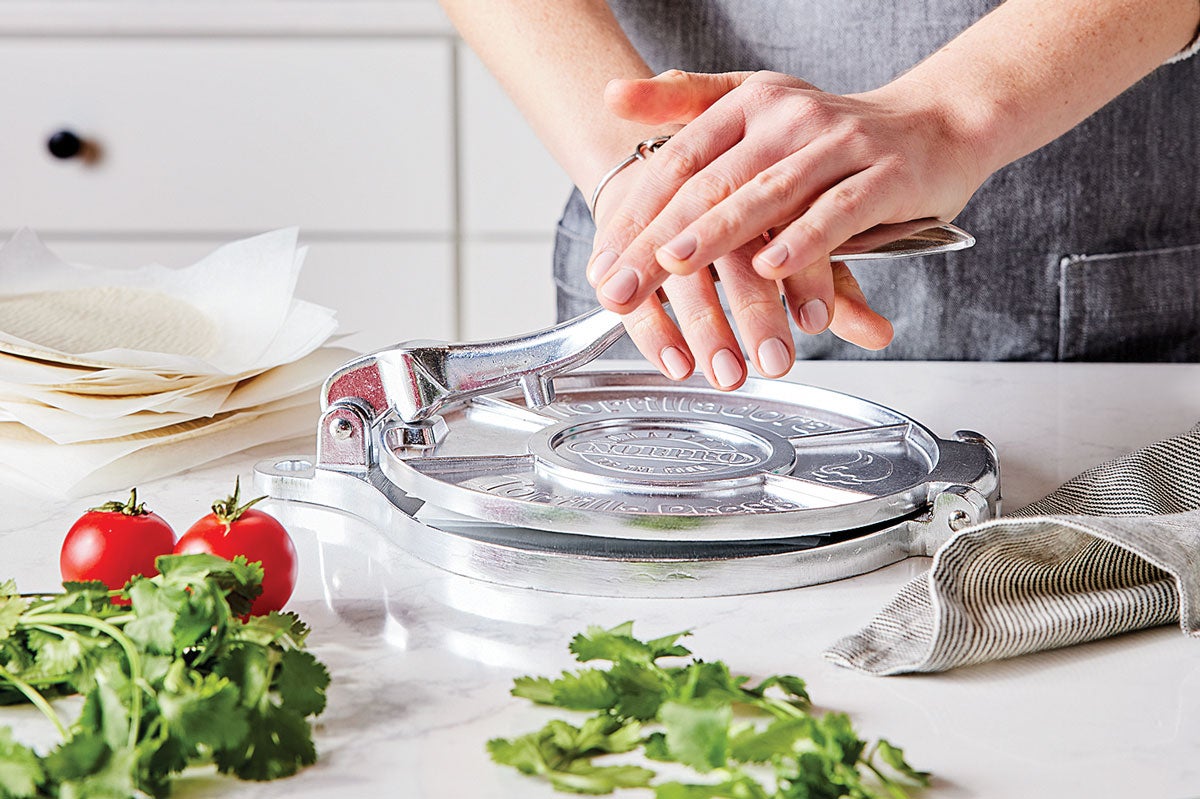 Hands pressing tortilla press