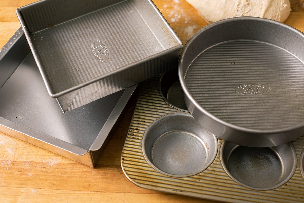 A stack of pans that can be used to make homemade hamburger buns on a kitchen table