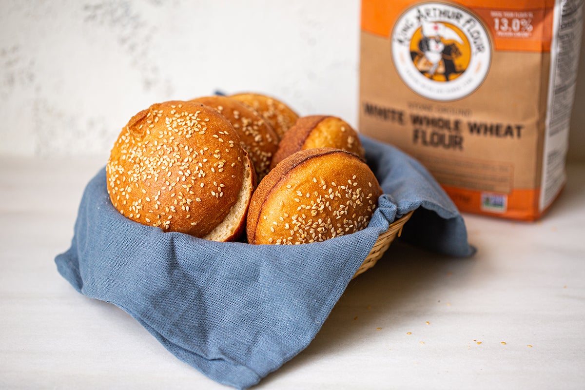 A basket of whole wheat hamburger buns and a bag of King Arthur White Whole Wheat Flour