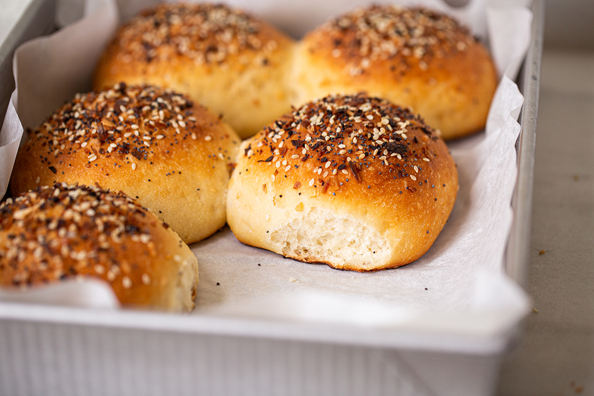 Homemade hamburger buns that have been baked close together so the sides are soft