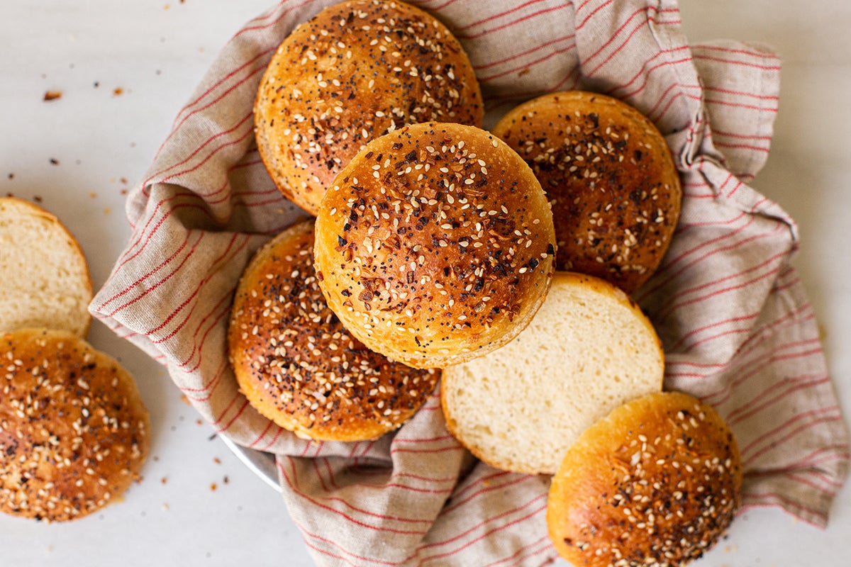 Petits pains à hamburger faits maison avec Tout le garniture de Bagel, fendus et dans un panier