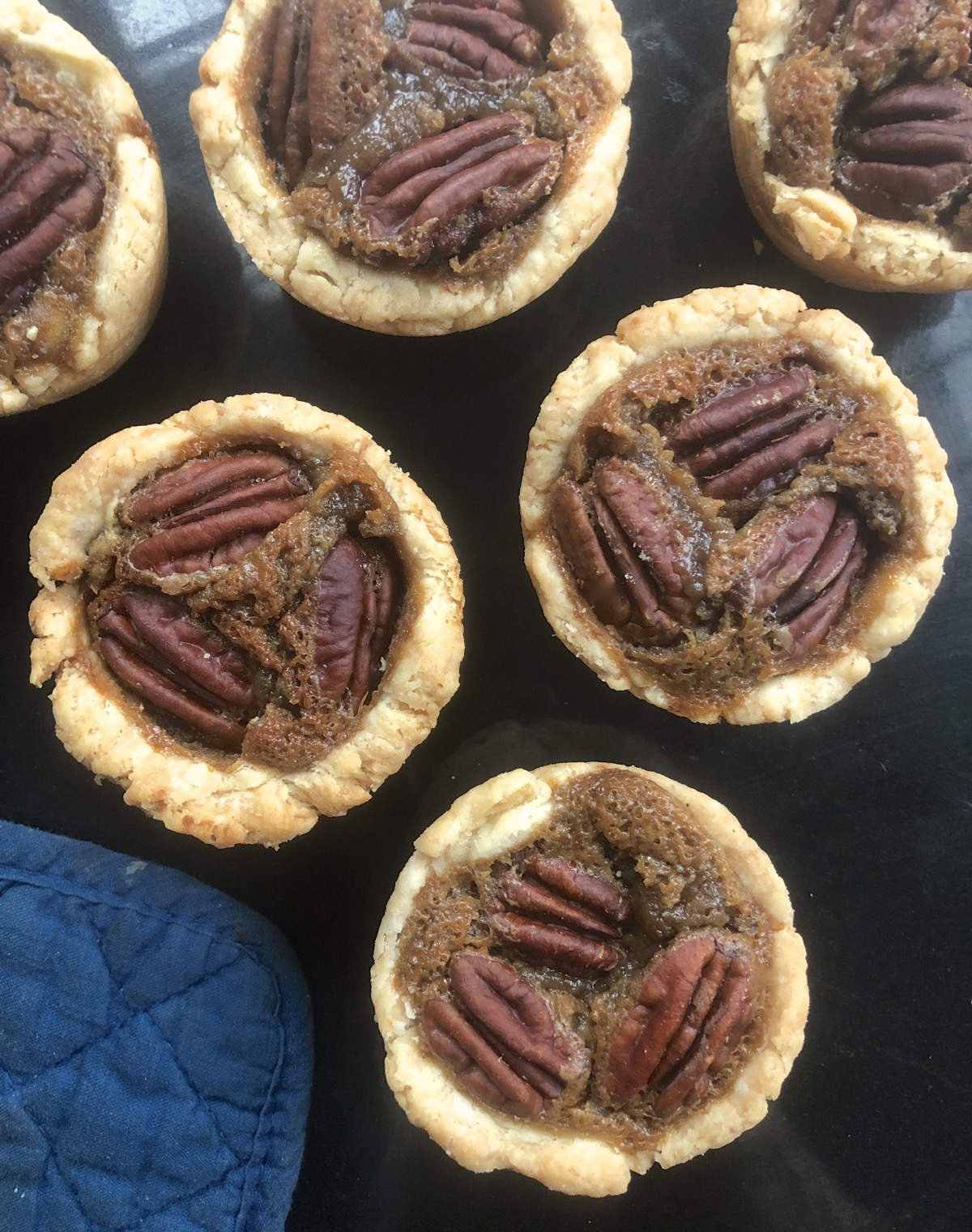 Mini pecan pies on a piece of black marble.