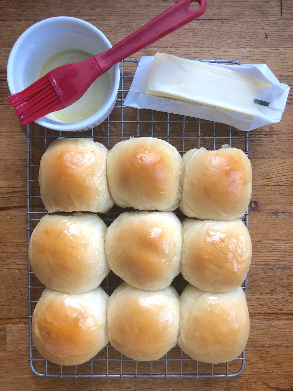 Pull-apart dinner rolls, brushed with melted butter, on a cooling rack