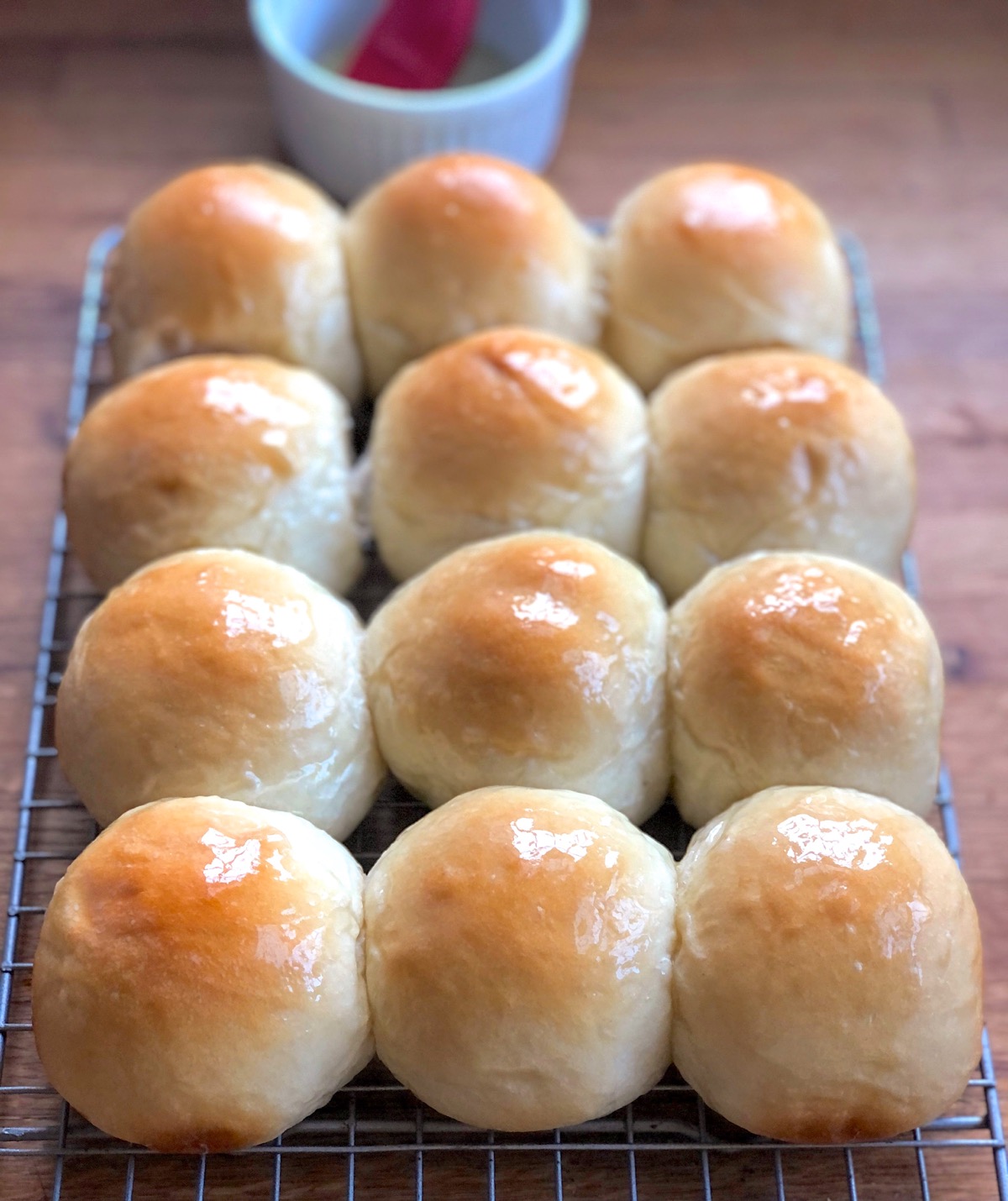 Golden pull-apart butter buns on a cooling rack, glistening from a brushing of melted butter.