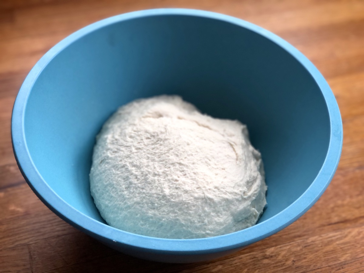 Soft dough in a blue bowl, ready to rise.
