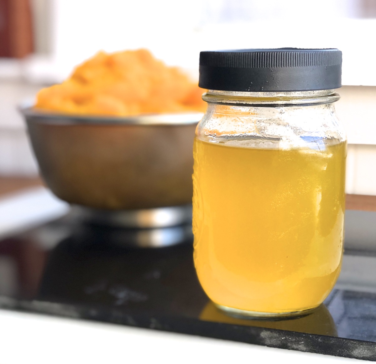 Jar of golden-orange liquid drained from pumpkin purée.