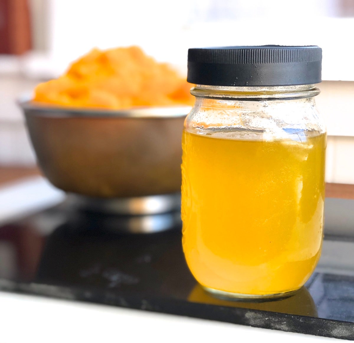 Jar of golden-orange liquid drained from pumpkin purée.