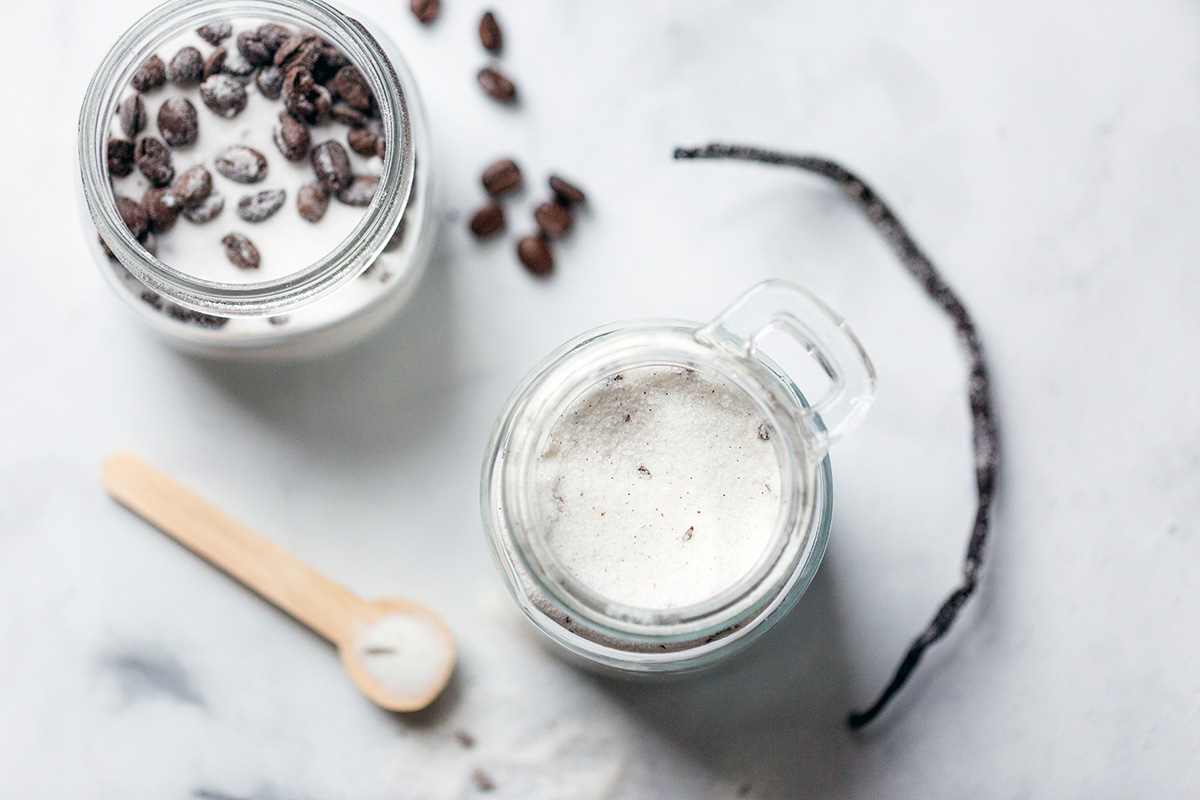 A jar of coffee sugar and vanilla sugar next to a vanilla bean on a kitchen table