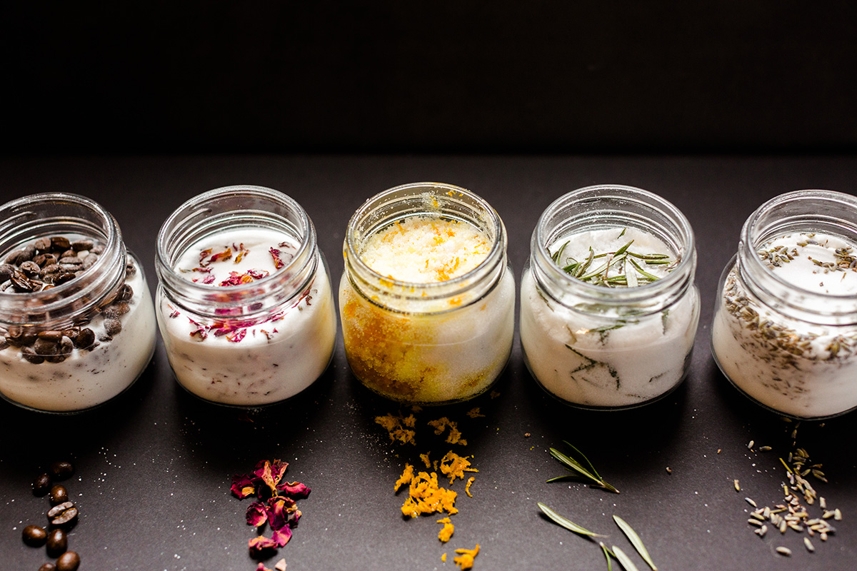 Small mason jars with infused sugar lined up: vanilla sugar, citrus sugar, rosemary sugar, and lavender sugar