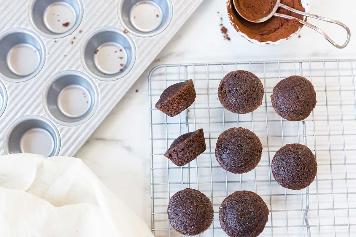 A mini muffin pan and madeleines shaped like mini muffins on a cooling rack 