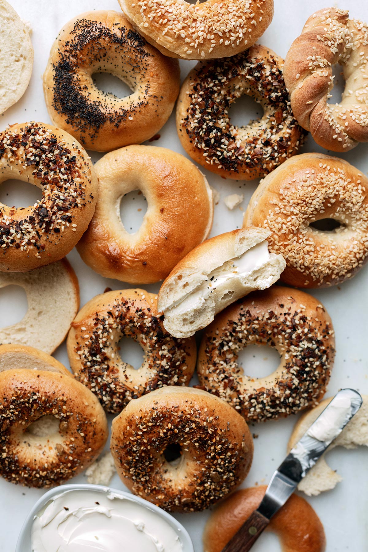 Assorted homemade bagels, some split in half and filled with cream cheese