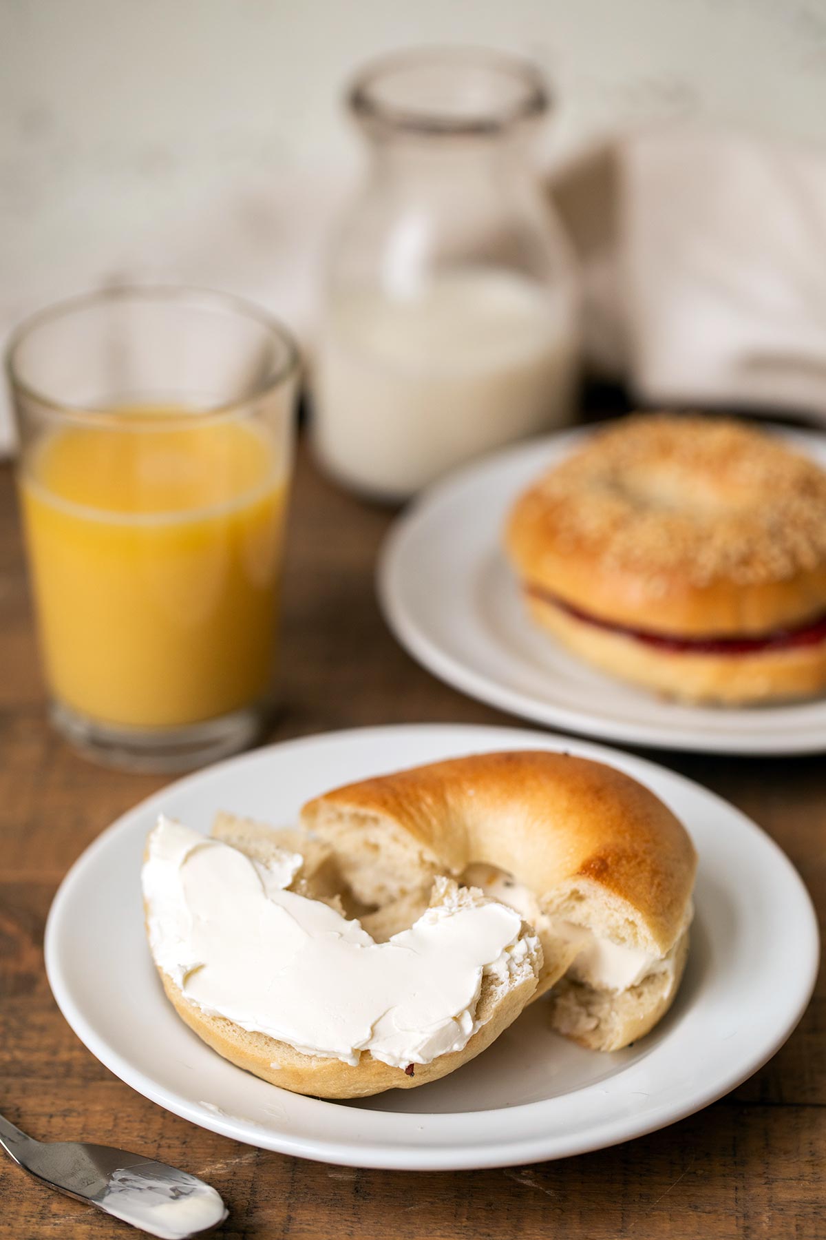 A homemade bagel split in half and spread with cream cheese