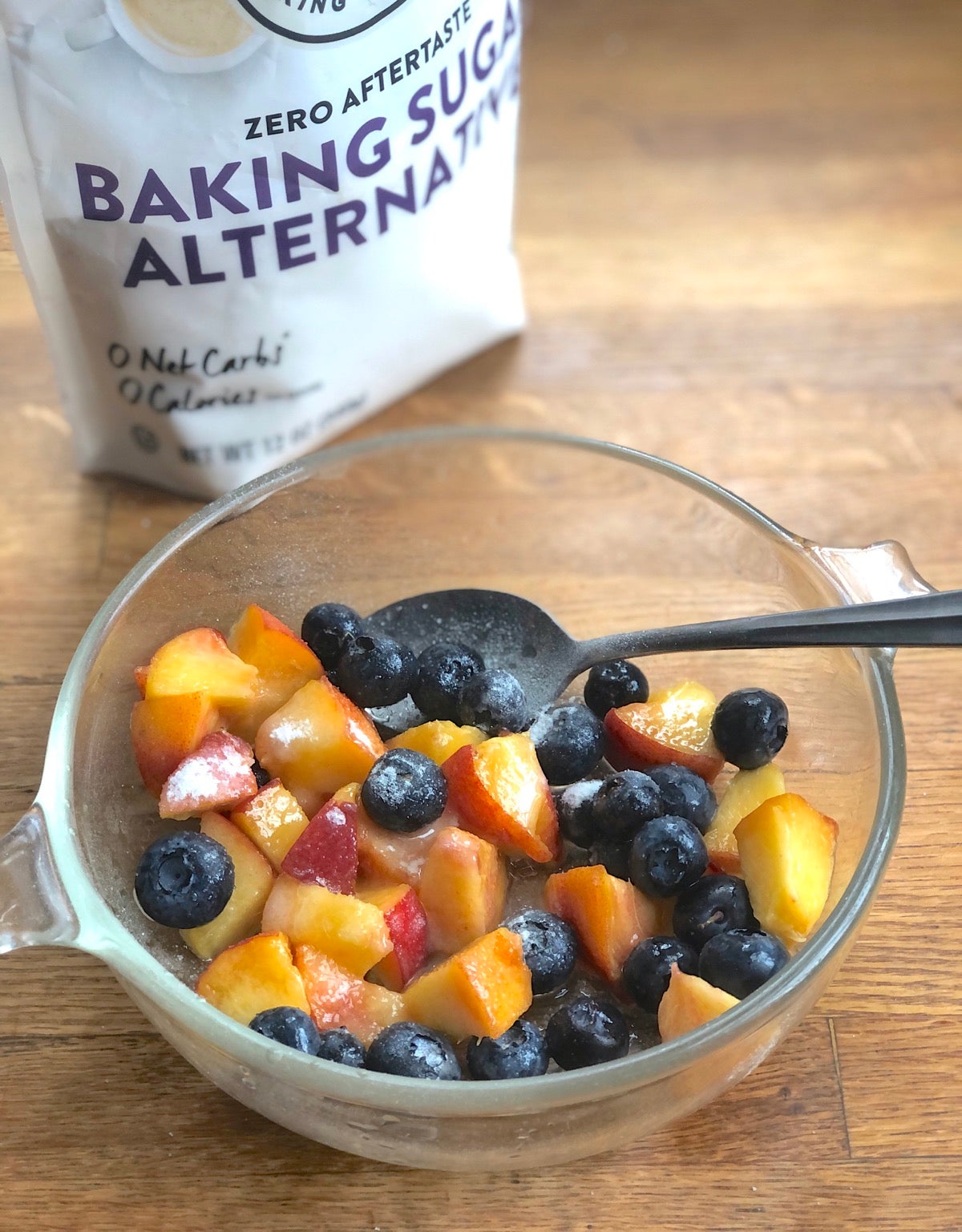 Fresh blueberries and diced peaches in a bowl with alternative confectioners' sugar sprinkled on top, to sweeten.