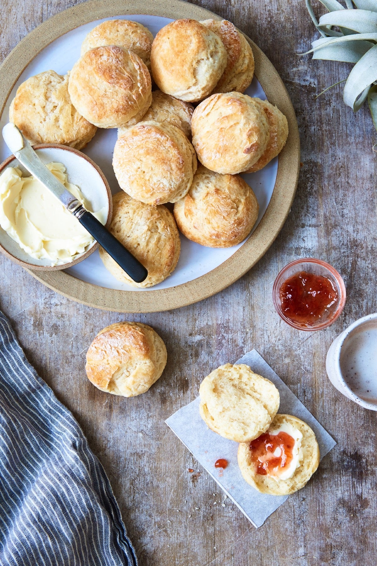 Angel Biscuits on a plate, one biscuit split open and buttered on a saucer.