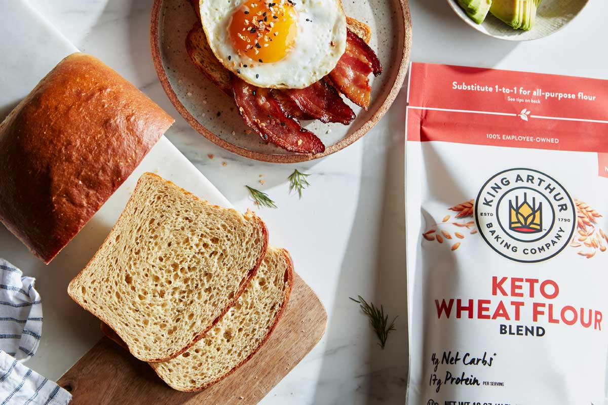 Sliced keto bread next to flour bag and breakfast spread