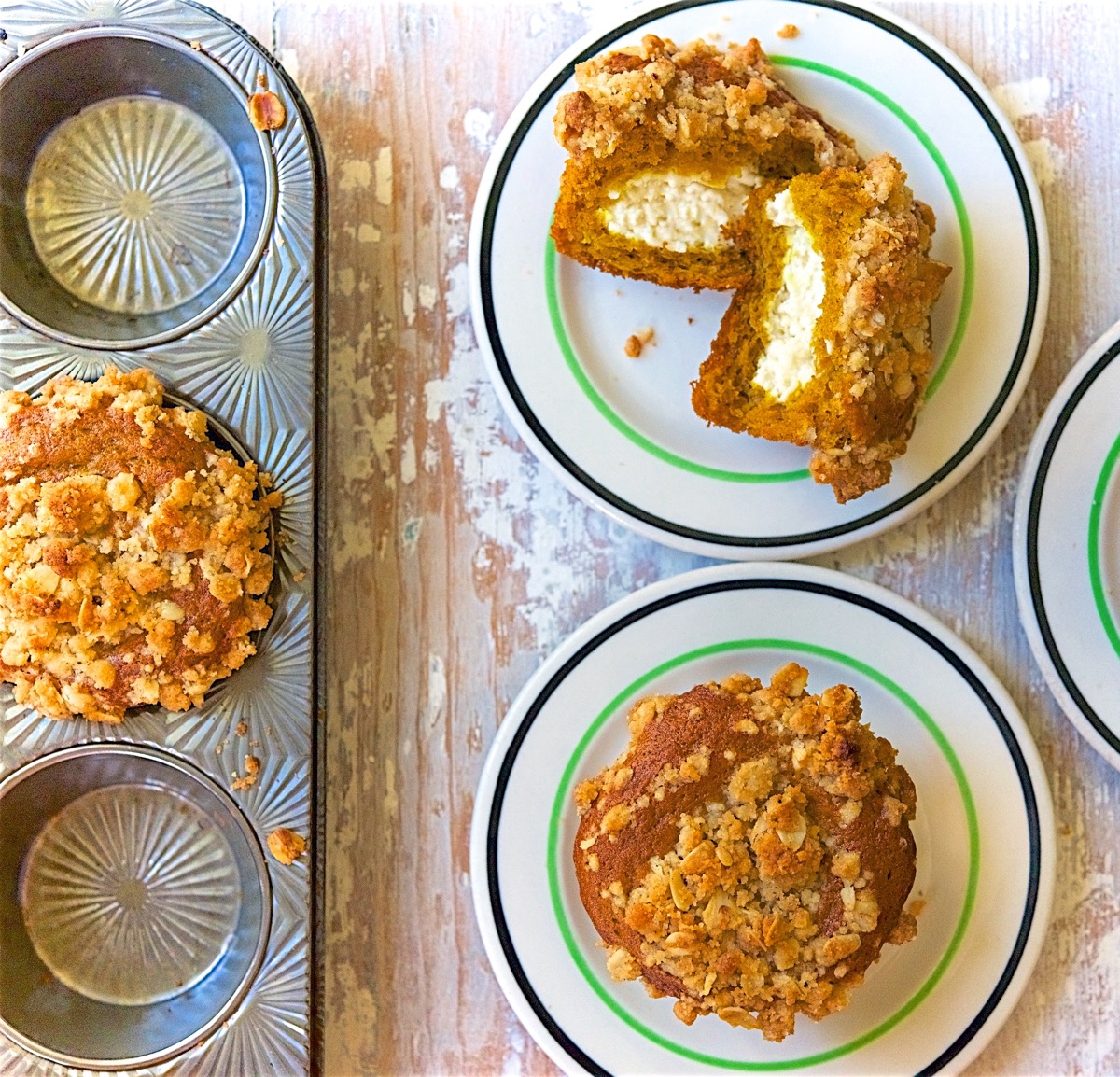 Cream cheese-filled pumpkin muffins on two plates, one cut open