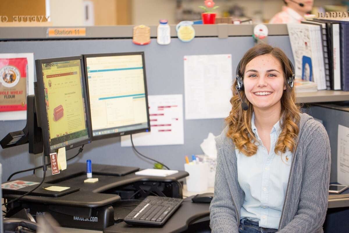 Woman sitting at desk wearing headphones.