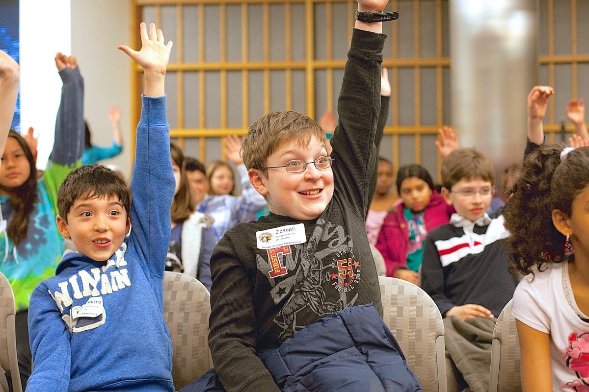 Children raising their hands during a baking class.