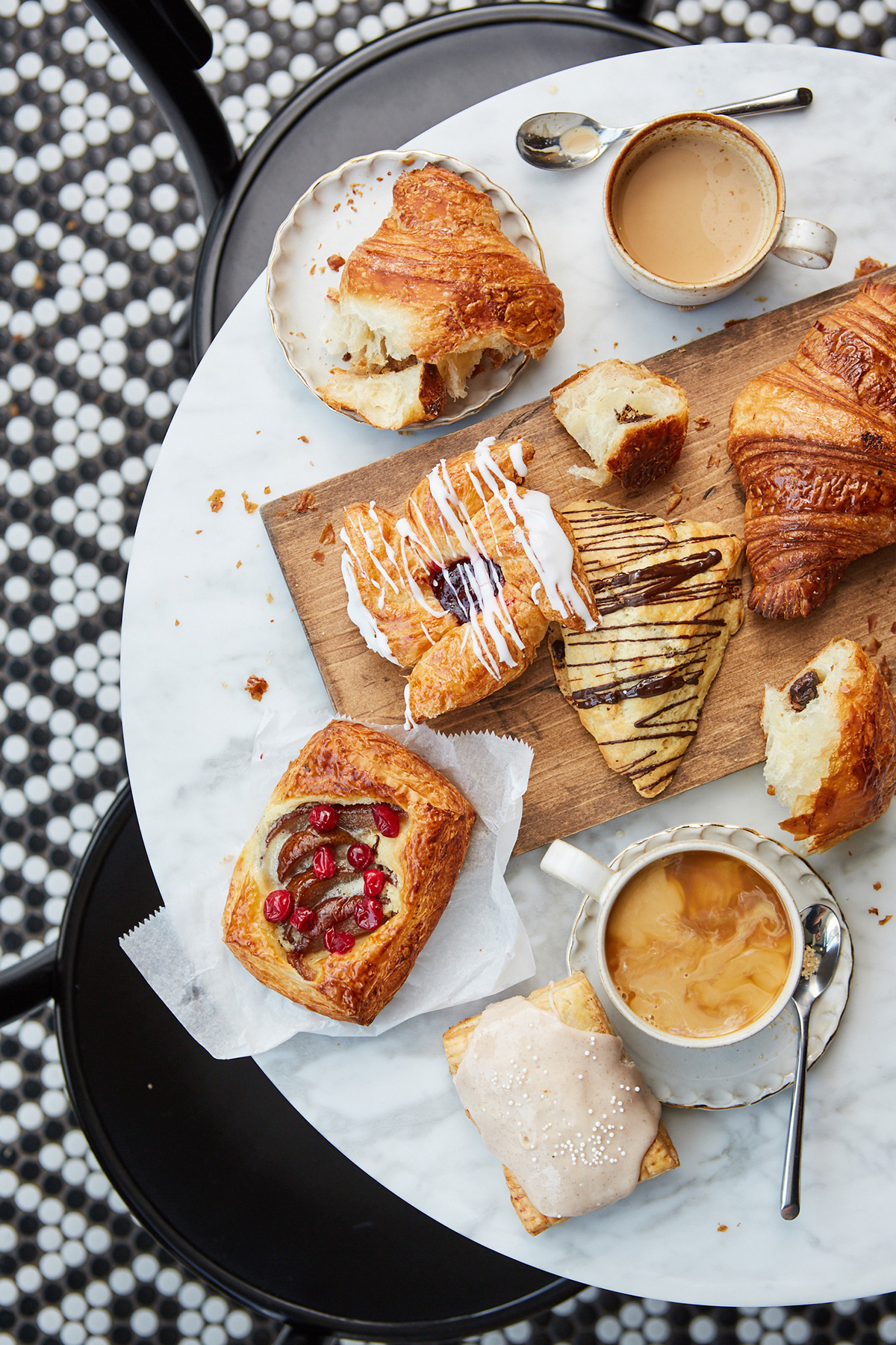 overhead shot of croissants, pastries, and coffee on marble table