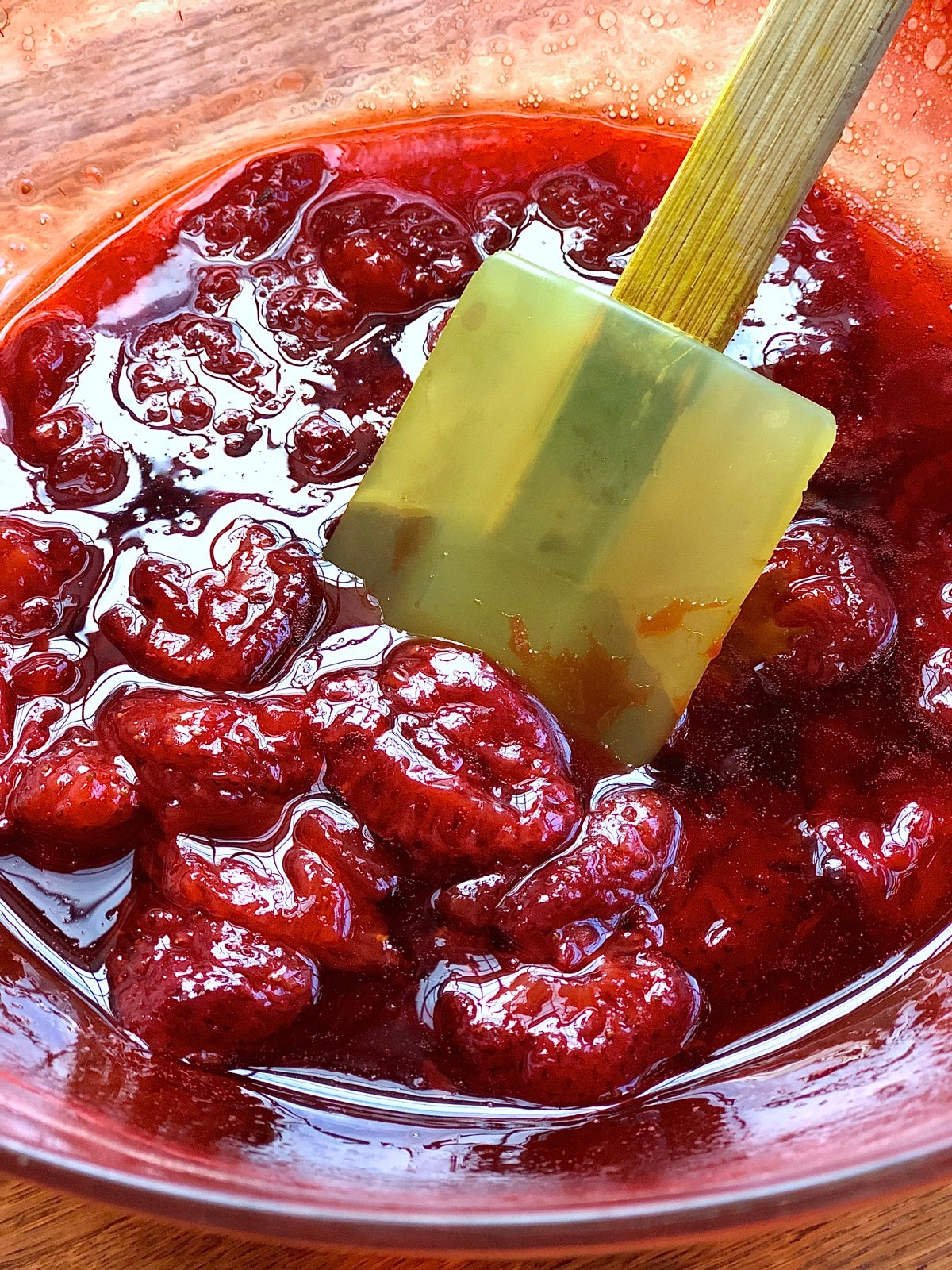 Bowl of cut strawberries and sugar after 10 minutes in the microwave — looking syrupy.