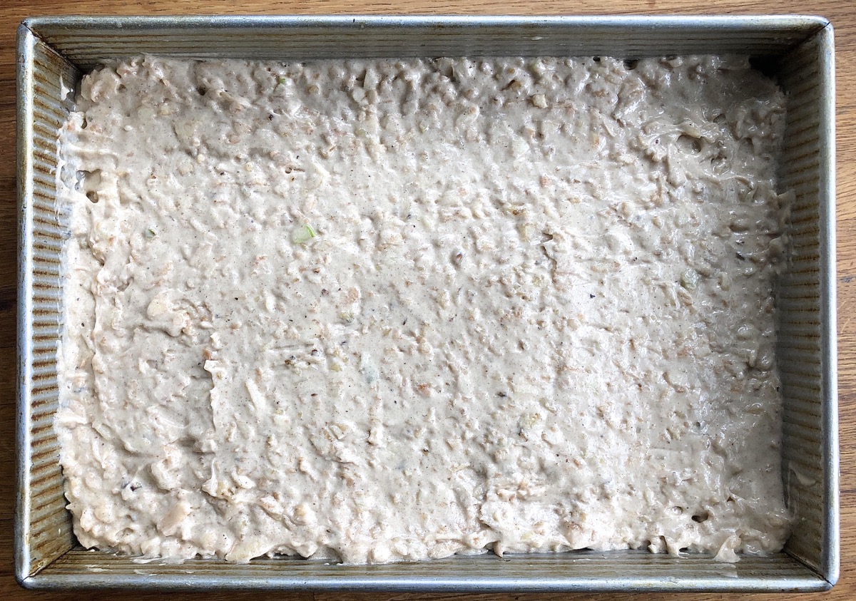 Apple cake batter scooped into a 9" x 13" baking pan and smoothed down.