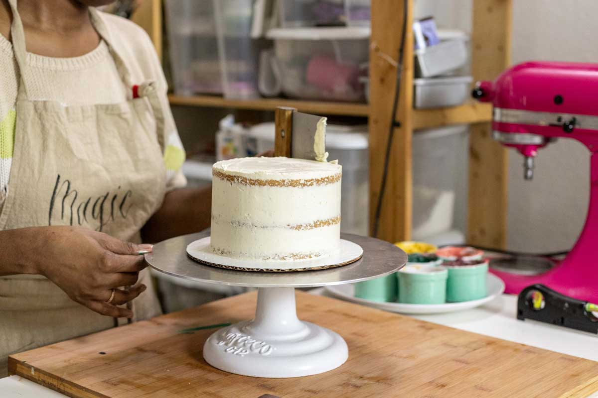 Using bench scraper to smooth sides of cake