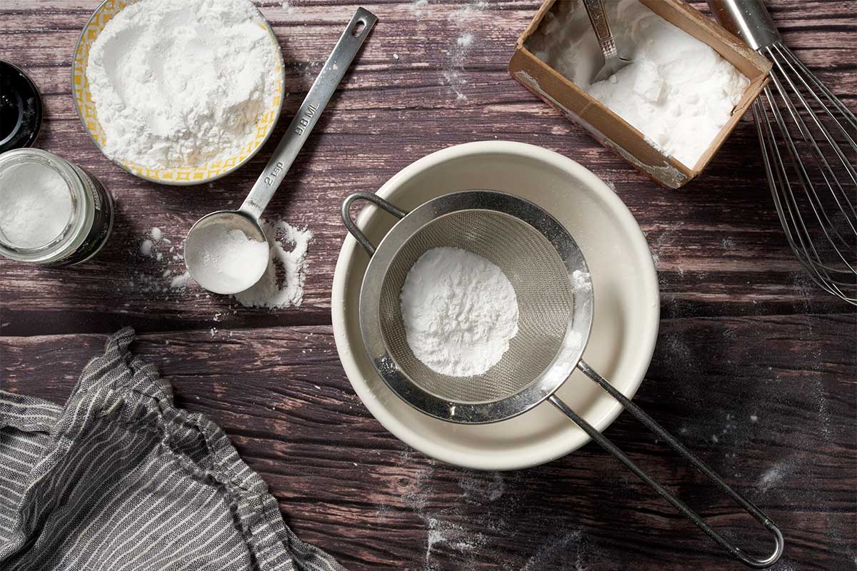 A small sifter and little bowls of baking soda and cream of tartar, which will be used to make homemade baking powder