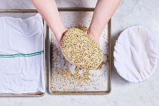 Adding seasoning to Parmesan Black Pepper Sourdough bread before baking.
