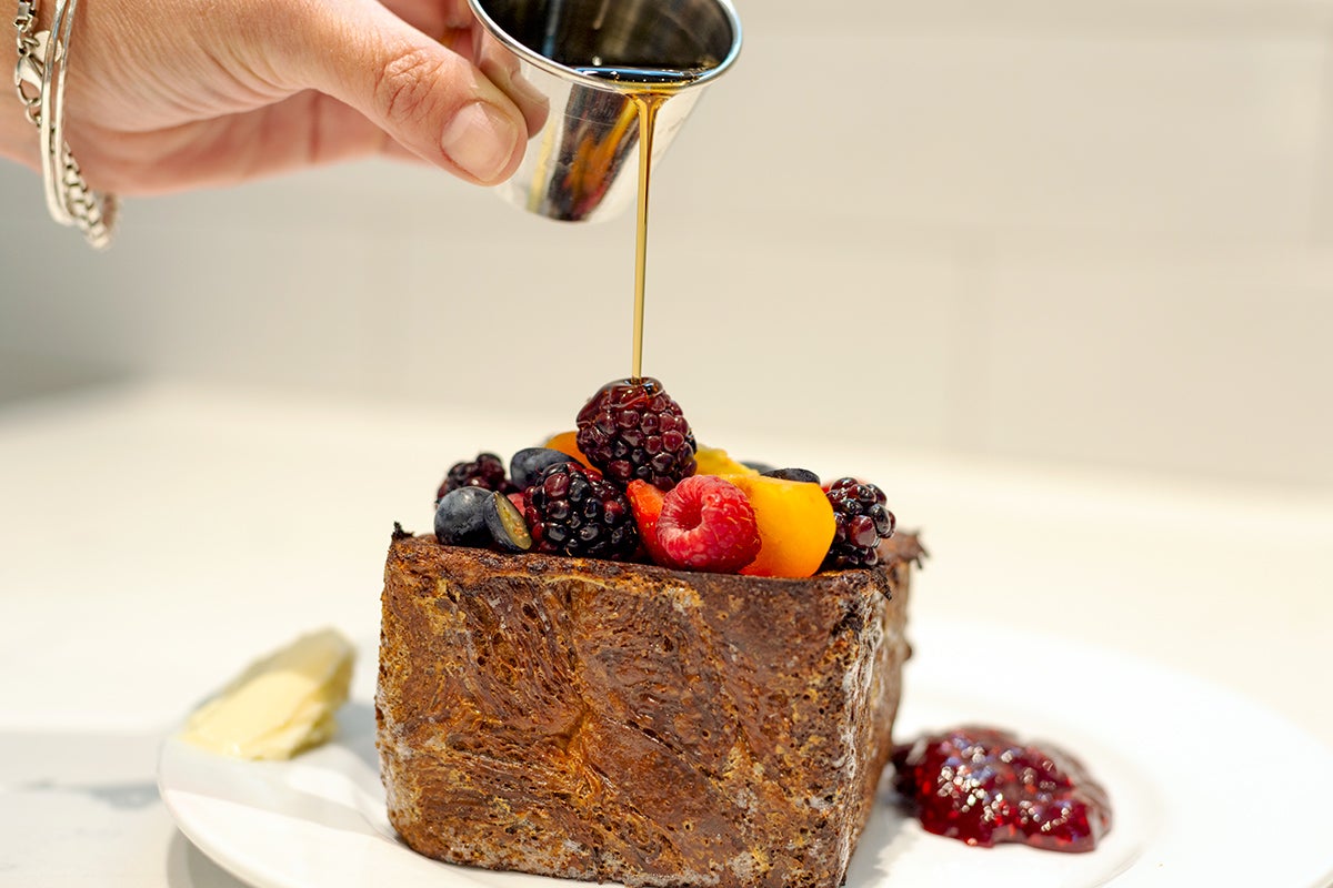 syrup being poured on fruit-topped pastry