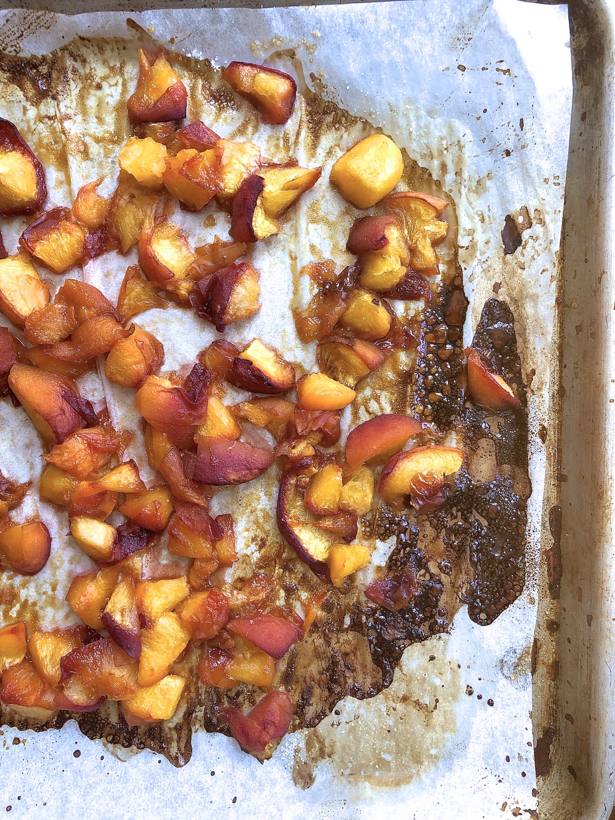 Roasted peaches on a parchment-lined baking sheet, ready to add to peach scone dough.
