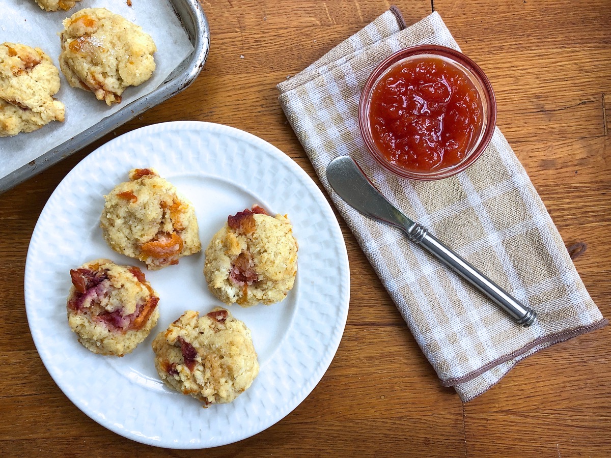 Mini peach scones made with roasted peaches on a serving plate, with peach preserves.
