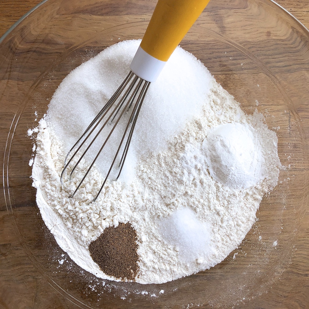 Flour, salt, sugar, baking powder, and nutmeg in a mixing bowl, ready to be whisked together.