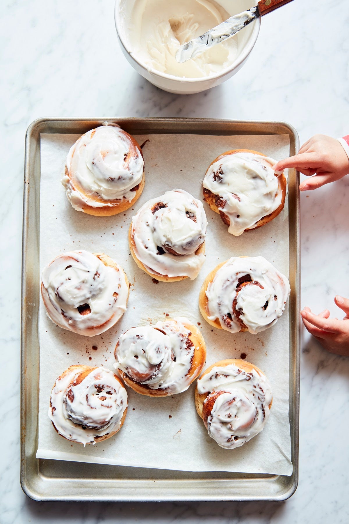 Iced cinnamon rolls on a baking sheet.