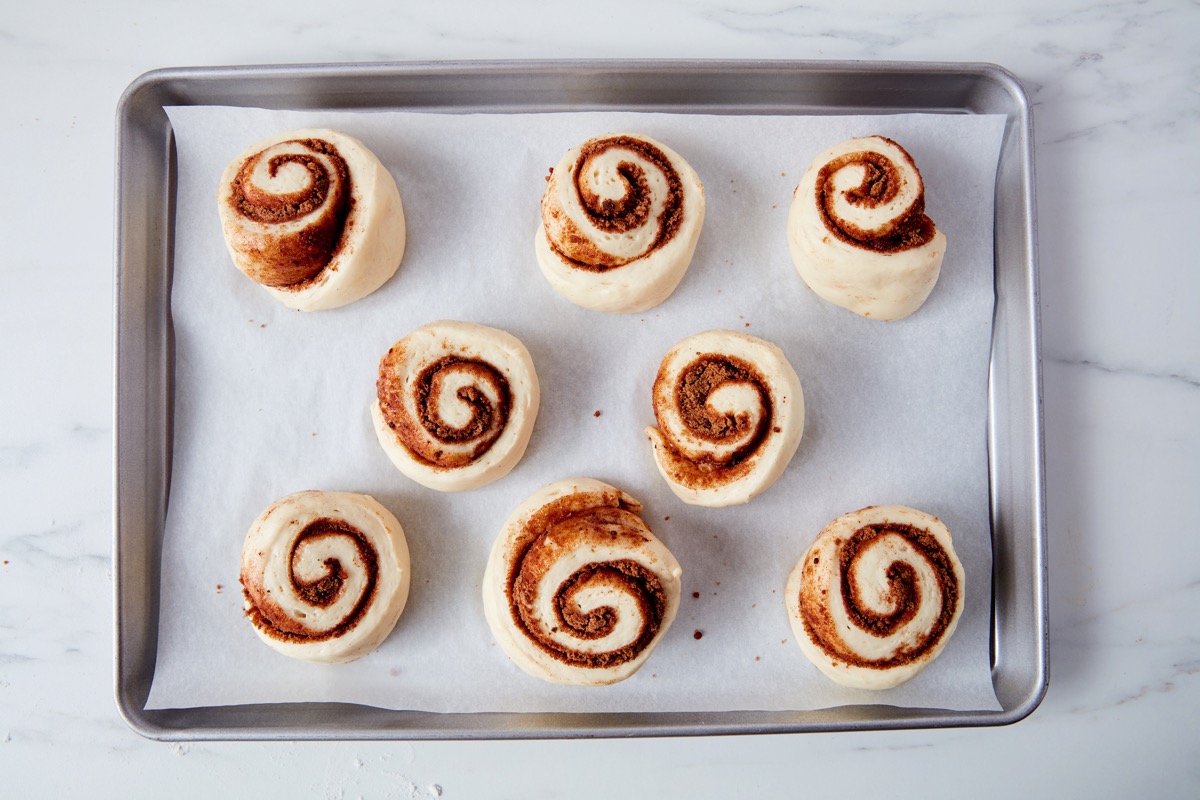 Cinnamon buns on a baking sheet, ready to rise and bake.